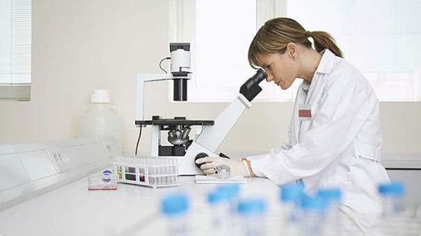 Embryologist in laboratory looking through microscope